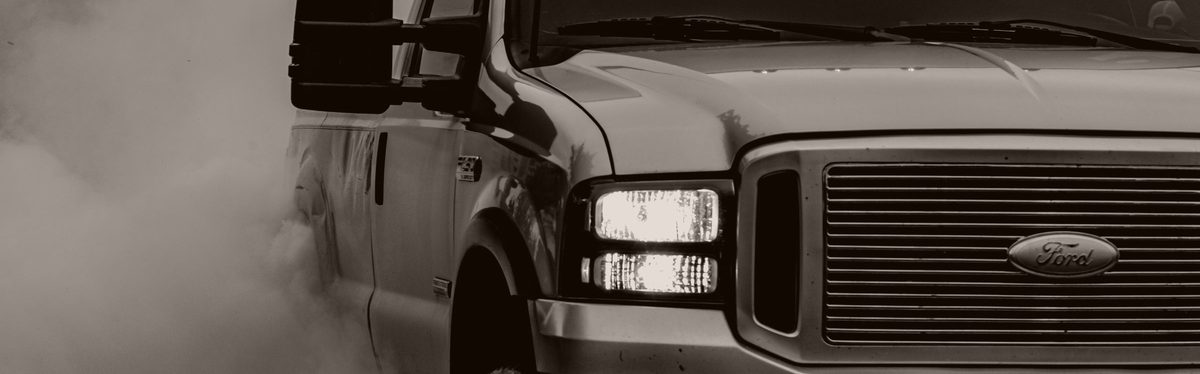 A pickup truck in black and white, surrounded by dark smoke
