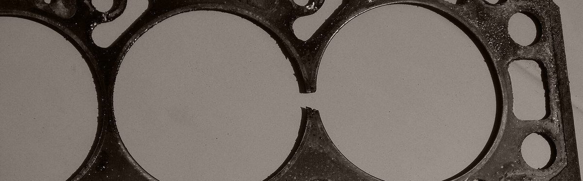 A used head gasket with its seal broken through between two cylinder openings