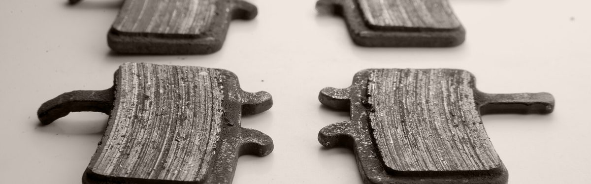 Four worn disc brake pads laid out side by side