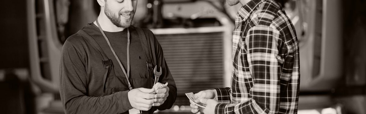 A mechanic taking payment from a customer in a workshop