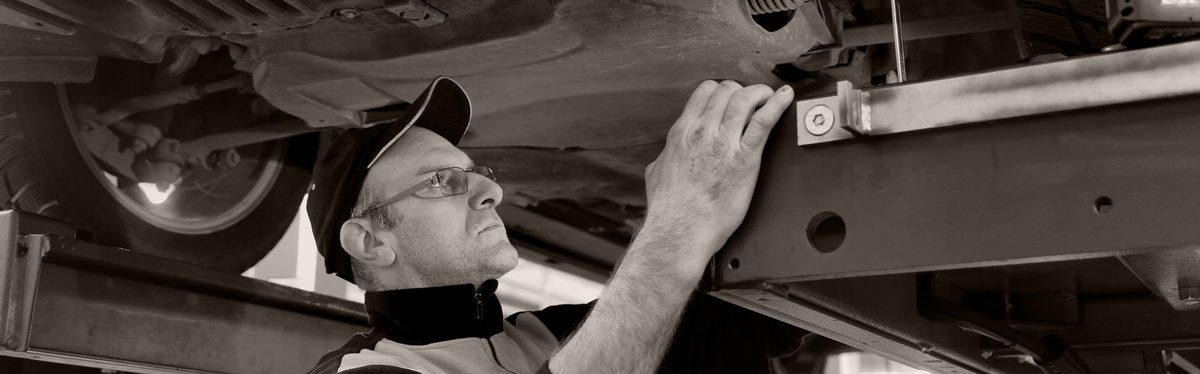 A mechanic working under a car raised on a lift
