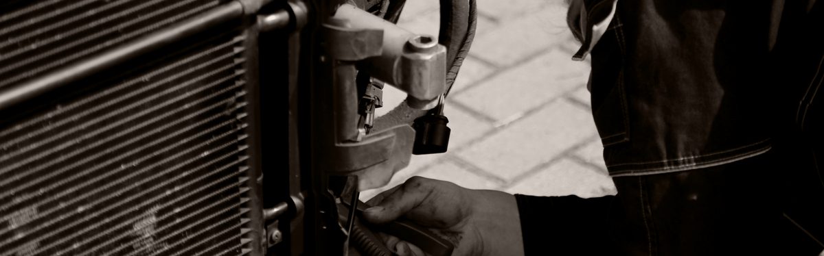 A mechanic working at the front of a radiator
