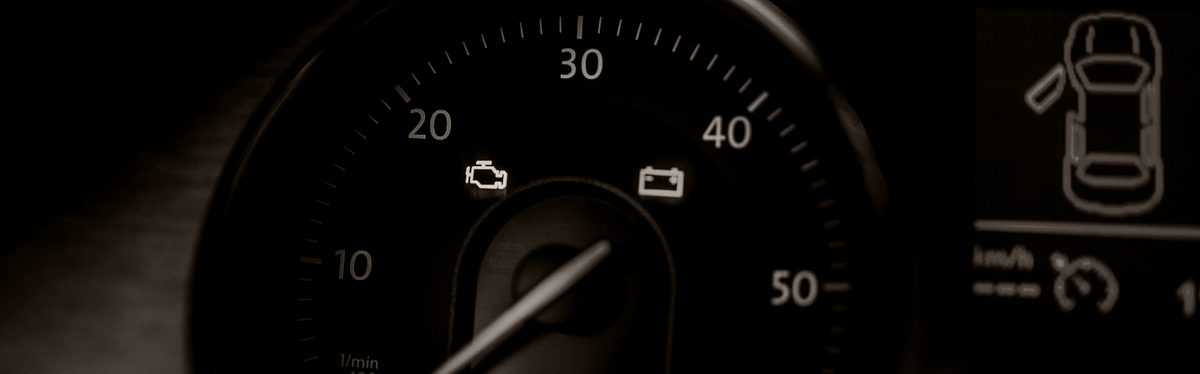 An instrument cluster with the amber check engine lamp and the red battery lamp lit on the tachometer