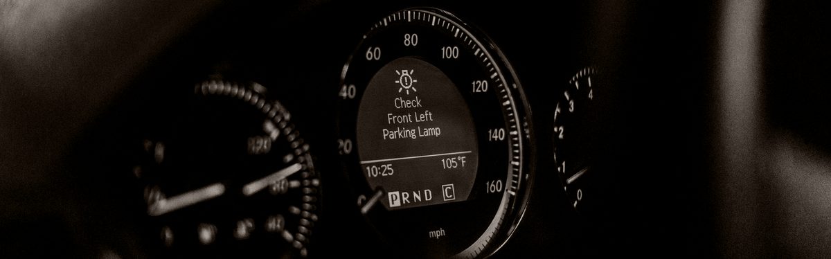 A car's instrument cluster with a warning lamp lit