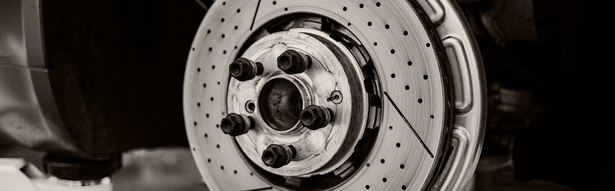 A drilled brake disc with the wheel removed, showing the hub face, its wheel studs and the center bore