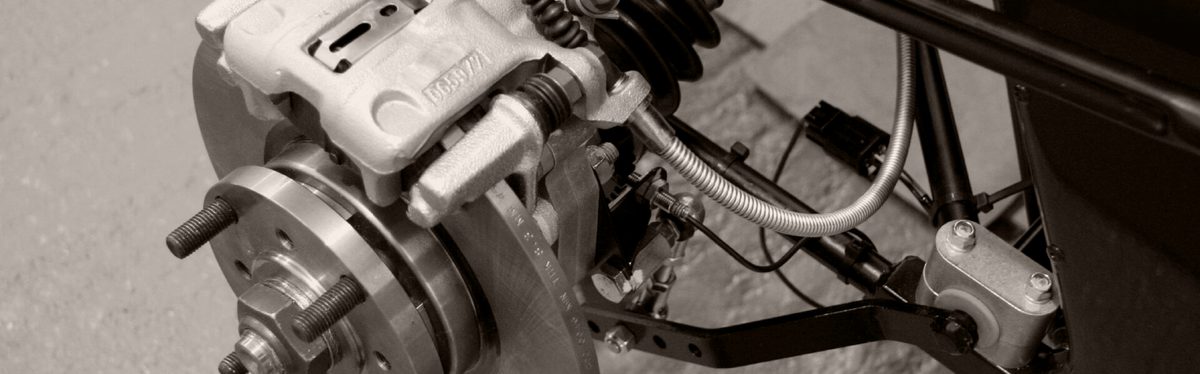 A wheel speed sensor bolted at a car's rear hub, its cable running off beside the brake disc and caliper