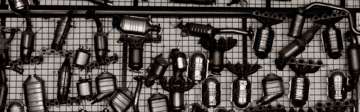 A wall of automotive exhaust parts on a workshop grid, shot square on