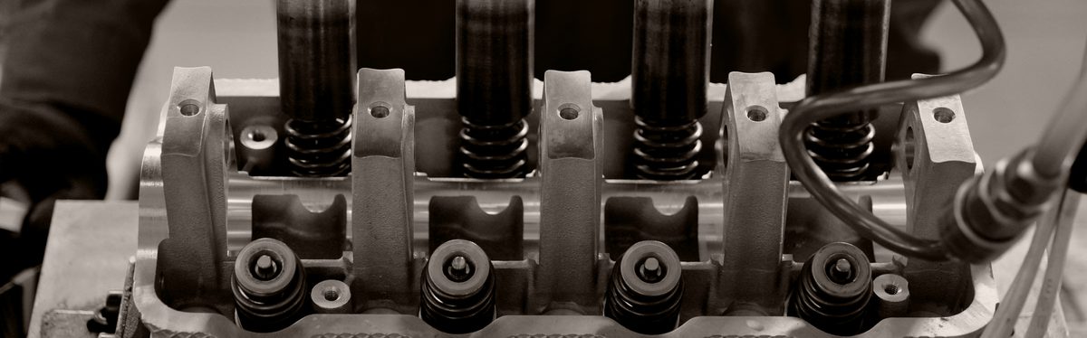 An engine cylinder head on a bench, its spark plug holes open