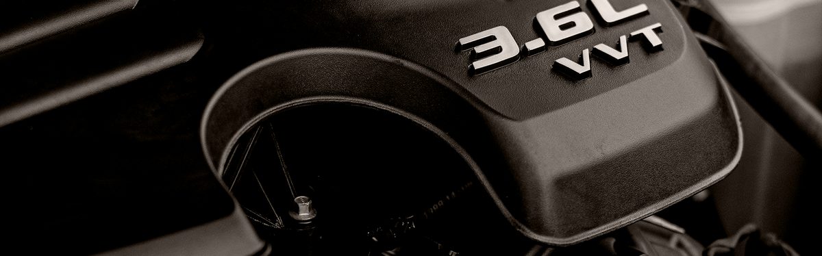 A V6 engine's plastic cover, marked 3.6L VVT, under an open hood