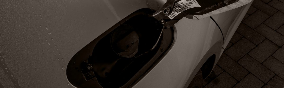 An open fuel filler door, the cap still screwed into the neck behind it