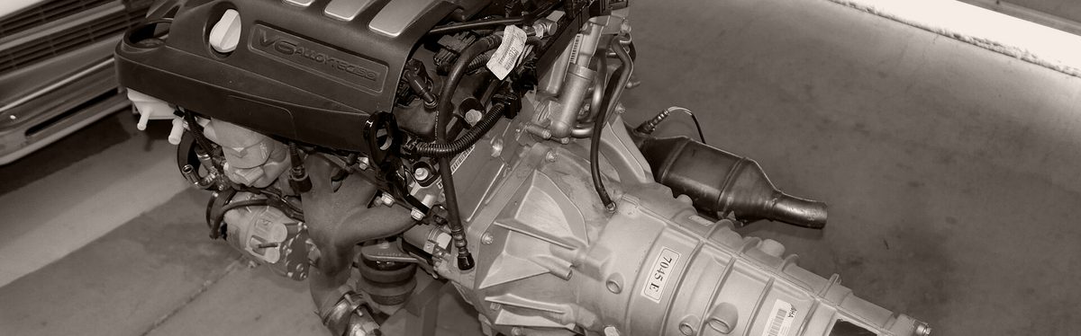 A V6 engine and its automatic transmission on a display stand, the case running back to the tail housing at the output end