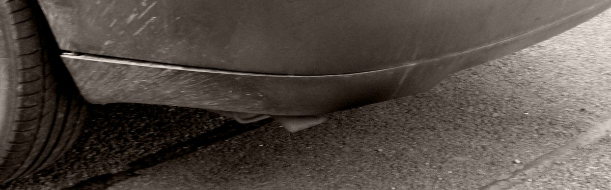 The tailpipe under the rear bumper of a parked hatchback