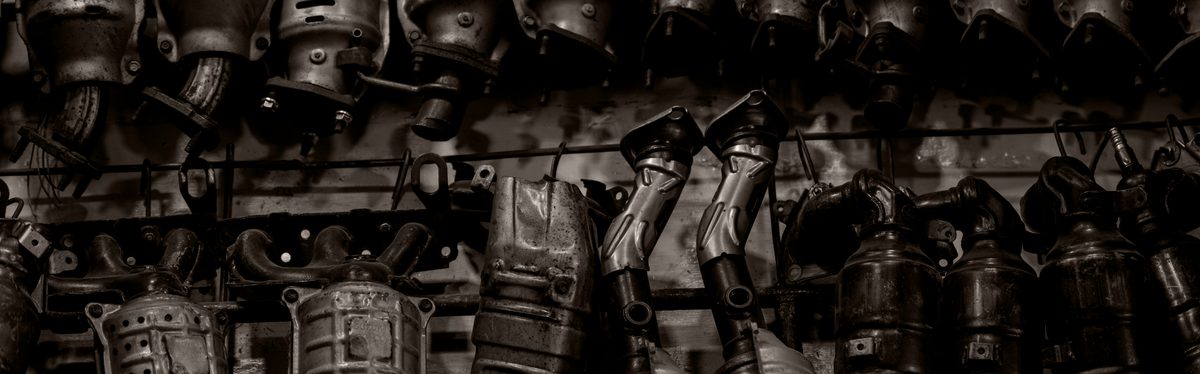 Used catalytic converters stacked on a workshop rack