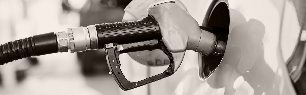 A fuel pump nozzle seated in the open fuel filler door of a white car