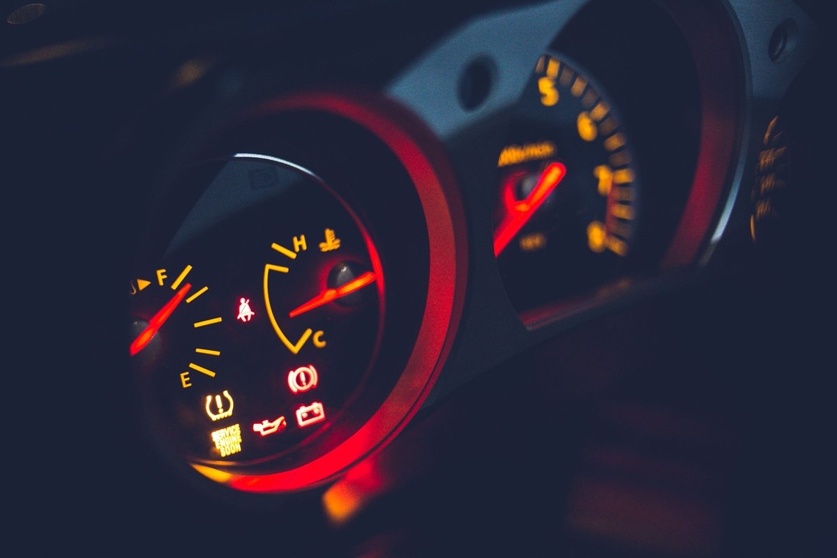 A car dashboard lit at night, the instrument cluster and its warning symbols glowing