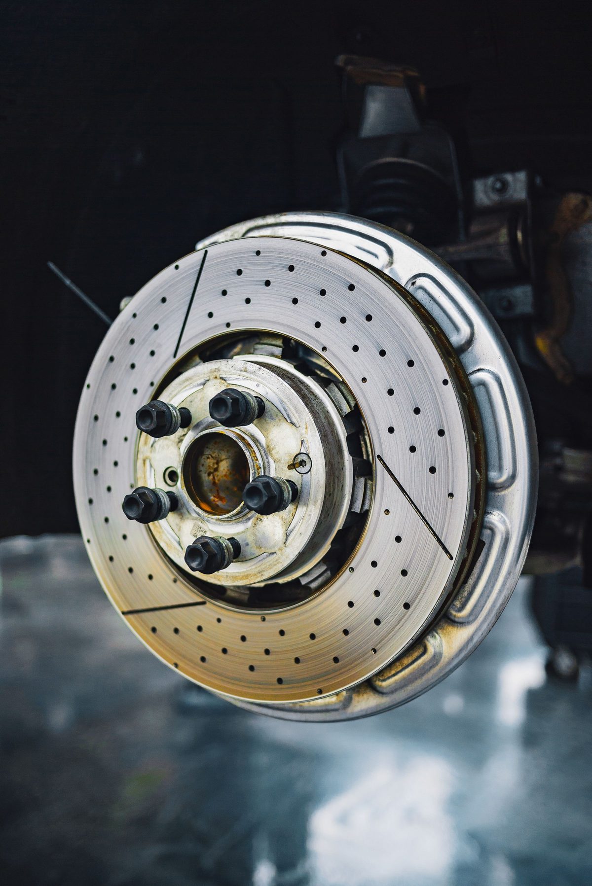 A drilled brake rotor on the hub with the wheel and caliper removed, the face of the rotor fully exposed