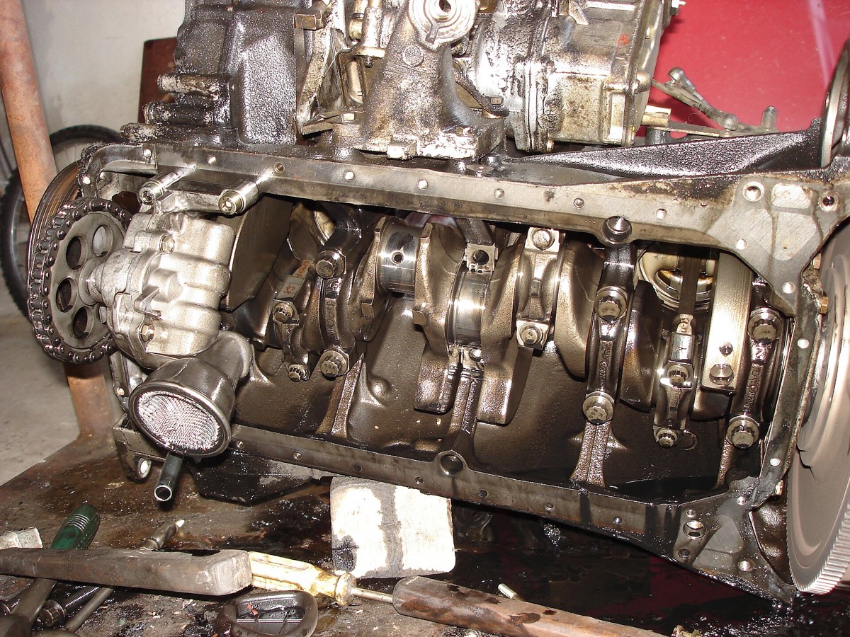 An engine upside down with the oil pan off, showing the crankshaft, the oil pump pickup screen and the sealing flange