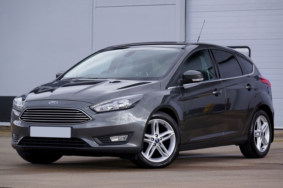 Dark gray Ford Focus hatchback parked outside a building, seen from the front and side