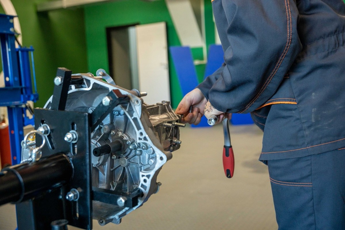 A mechanic working on an automatic transmission removed from a car in a workshop