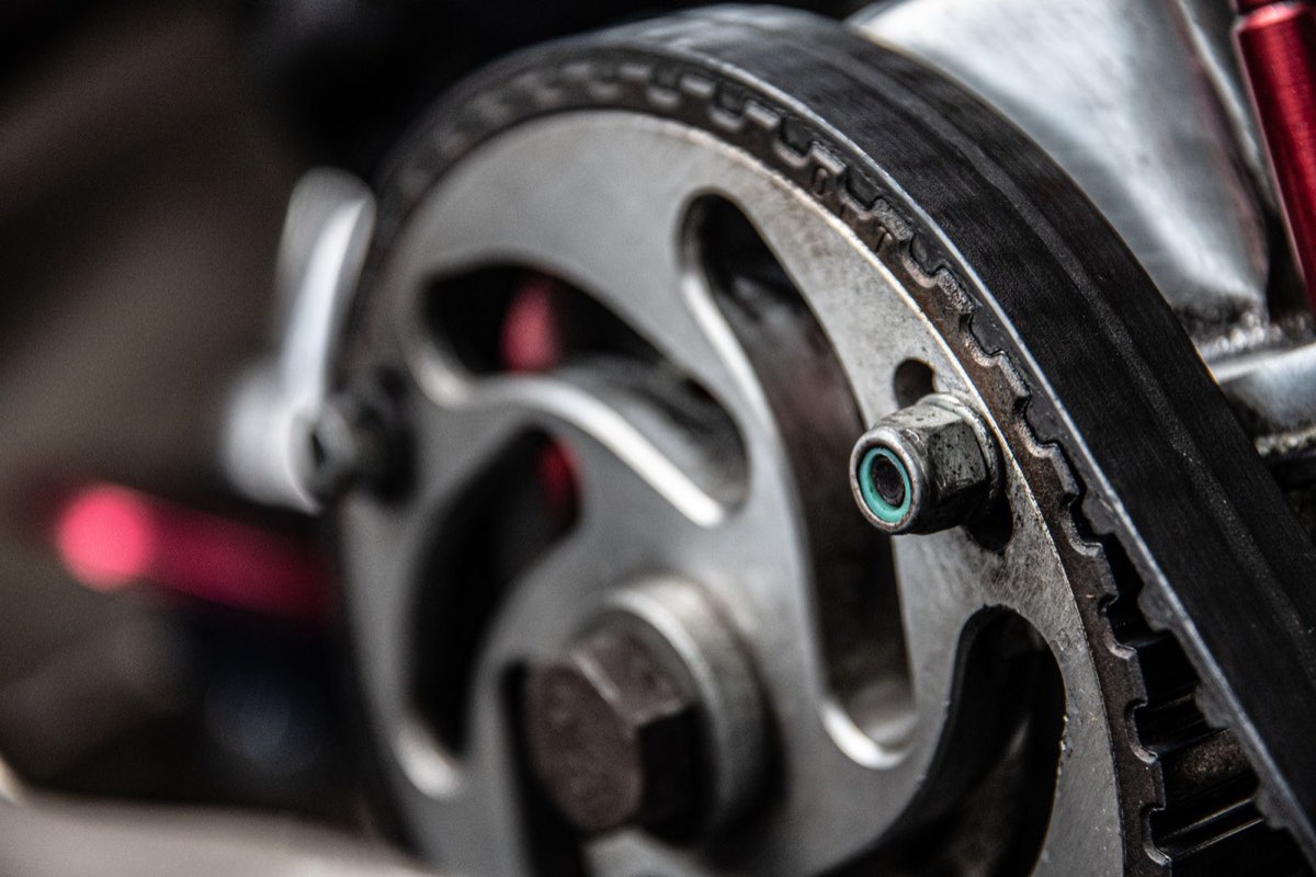 Close-up of a toothed timing belt running over a camshaft sprocket inside an engine